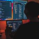 a man sitting in front of two computer monitors